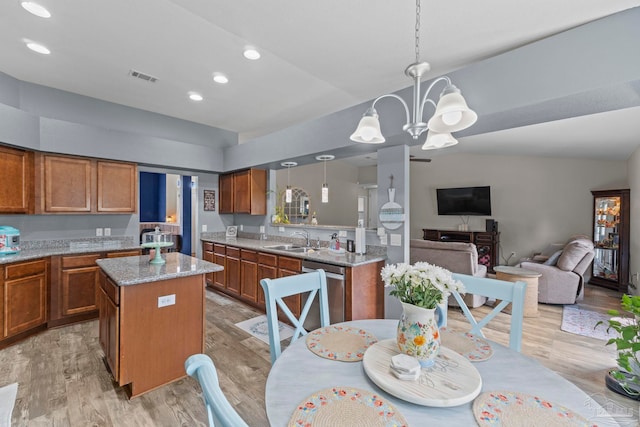 kitchen featuring visible vents, a chandelier, open floor plan, brown cabinetry, and a sink