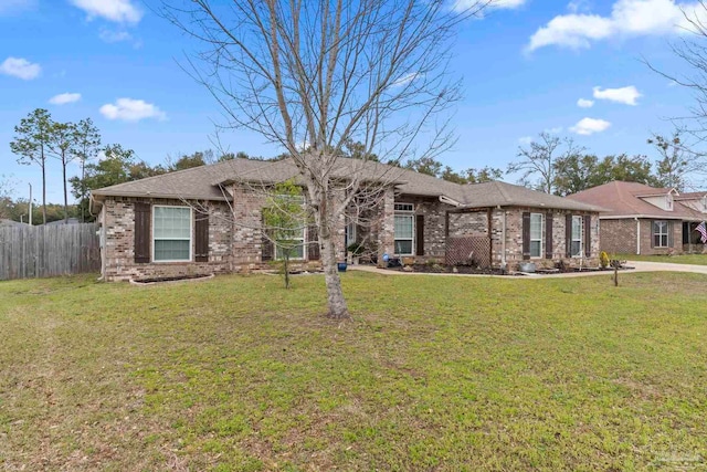 ranch-style home featuring brick siding, a shingled roof, a front lawn, and fence