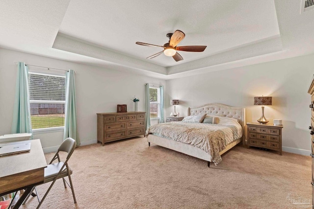 bedroom with a raised ceiling and light colored carpet