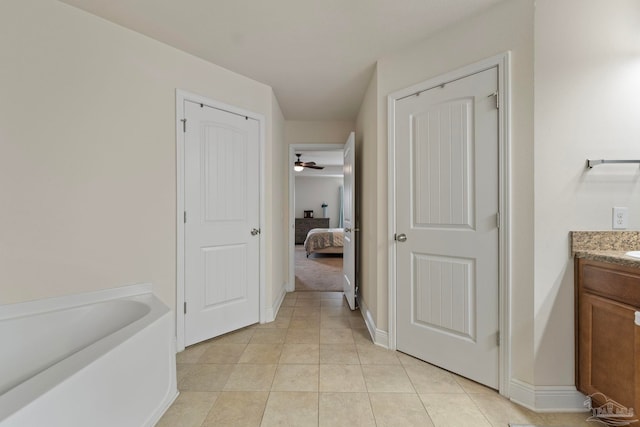 ensuite bathroom with connected bathroom, tile patterned flooring, baseboards, a bath, and vanity