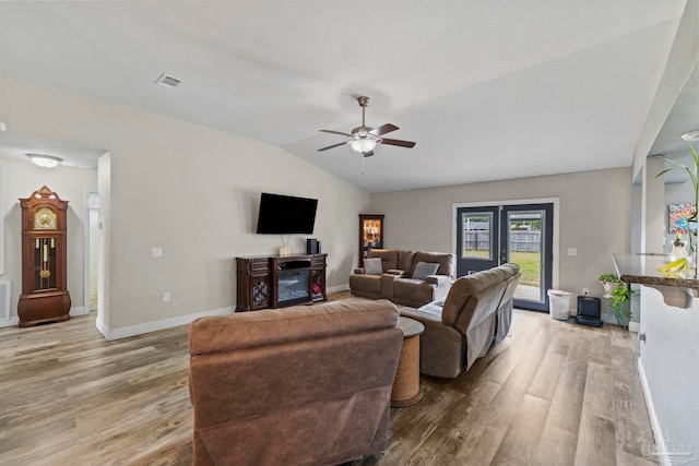 living area with visible vents, baseboards, ceiling fan, light wood-type flooring, and vaulted ceiling