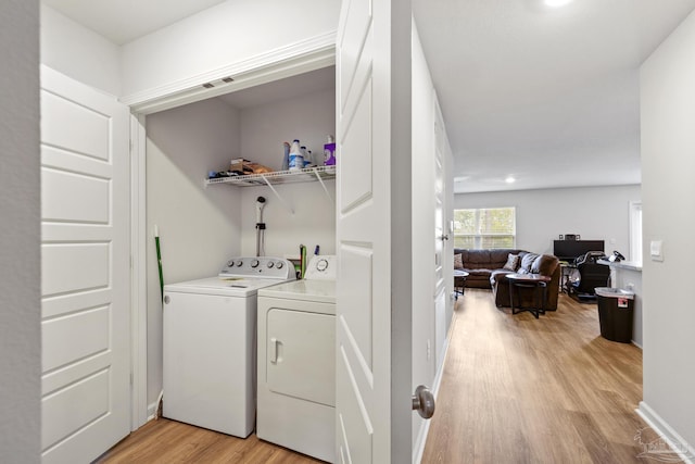 clothes washing area featuring washing machine and dryer and light hardwood / wood-style flooring