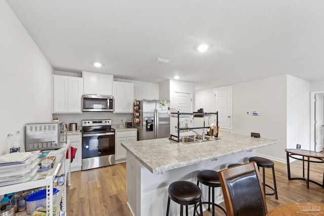 kitchen featuring a kitchen island, appliances with stainless steel finishes, sink, a breakfast bar area, and white cabinets