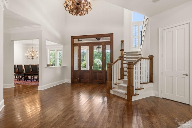 foyer entrance with a towering ceiling, ornamental molding, dark hardwood / wood-style flooring, and a chandelier