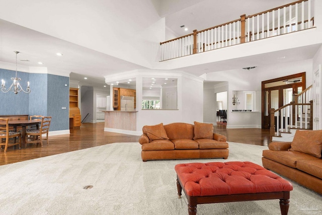 living room featuring crown molding, a towering ceiling, hardwood / wood-style floors, and a chandelier