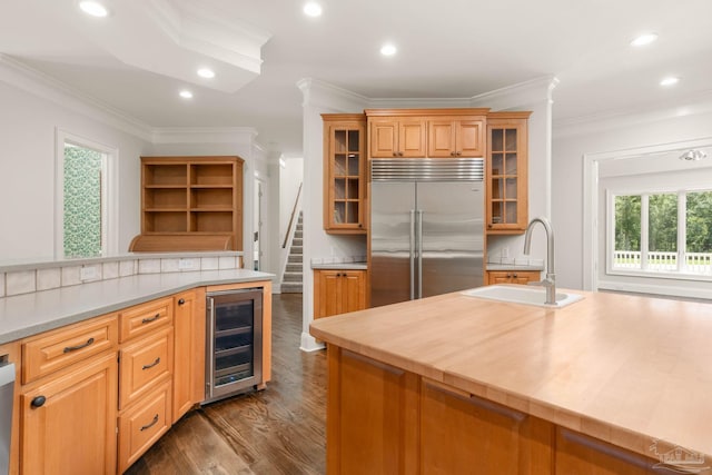 kitchen with appliances with stainless steel finishes, dark hardwood / wood-style floors, sink, beverage cooler, and crown molding