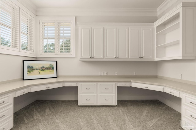 unfurnished office featuring crown molding, built in desk, and light colored carpet