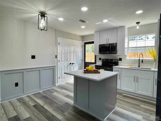 kitchen featuring light hardwood / wood-style flooring, a kitchen island, gray cabinets, range with electric cooktop, and sink