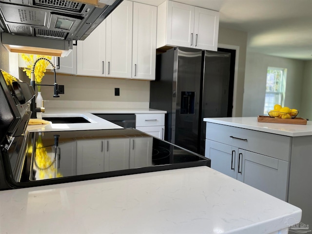 kitchen with white cabinets, stainless steel fridge, range hood, and sink