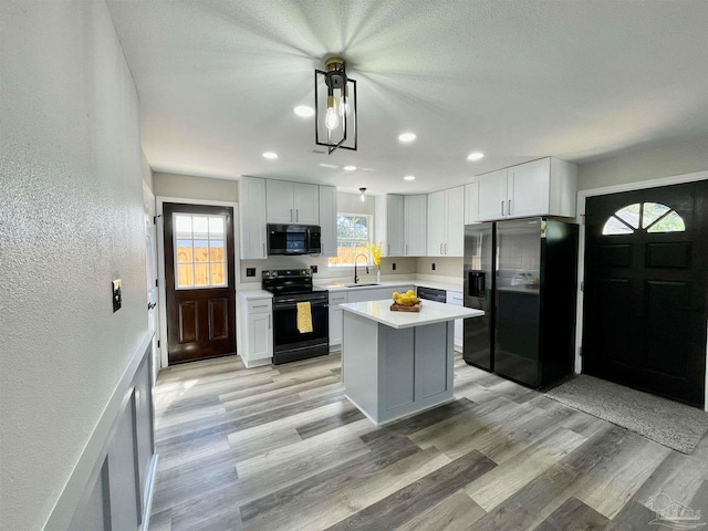 kitchen featuring light wood-type flooring, black appliances, sink, and a kitchen island