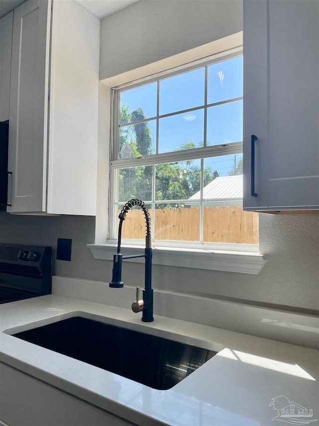 interior details with white cabinets, stove, and sink