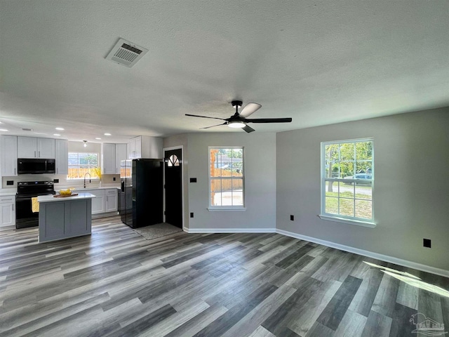 kitchen featuring black appliances, a wealth of natural light, hardwood / wood-style flooring, and ceiling fan