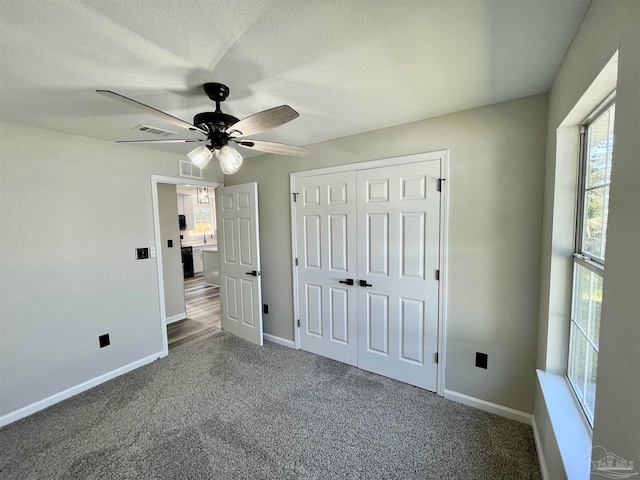 unfurnished bedroom featuring multiple windows, carpet floors, and ceiling fan