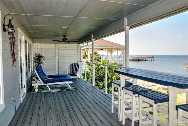 deck with ceiling fan and a water view