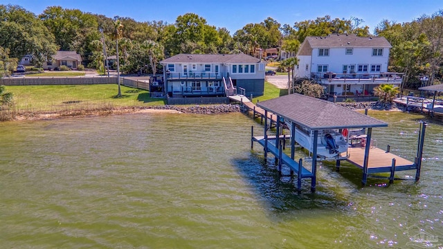 dock area with a deck with water view, a lawn, and boat lift