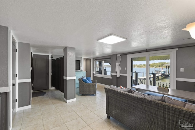 living room with light tile patterned floors, a textured ceiling, and baseboards