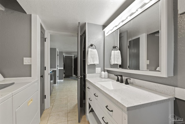 bathroom with a textured wall, tile patterned floors, washing machine and clothes dryer, a textured ceiling, and vanity