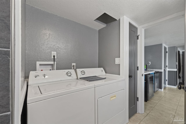 washroom with washer and clothes dryer, light tile patterned floors, a textured wall, a textured ceiling, and laundry area