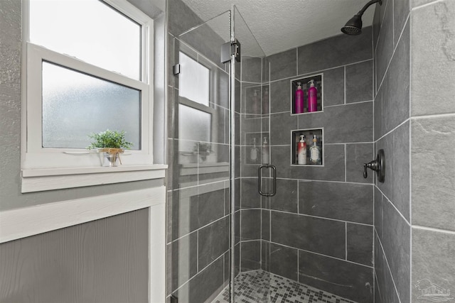 full bath with a textured ceiling and a stall shower