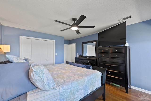 bedroom with visible vents, a ceiling fan, wood finished floors, a textured ceiling, and a closet