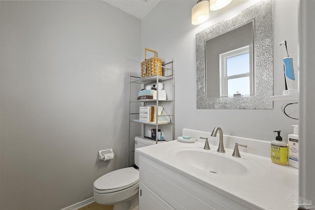 half bath with toilet, baseboards, and vanity