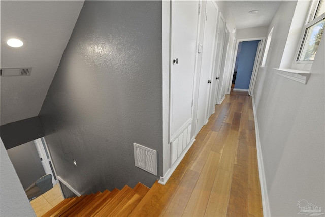 corridor with wood finished floors, visible vents, and baseboards