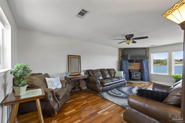 living room with a textured ceiling, ceiling fan, wood finished floors, visible vents, and baseboards