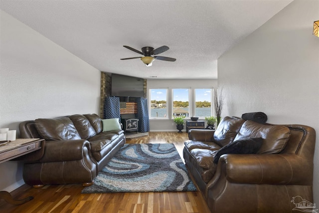 living area with a ceiling fan, a textured ceiling, baseboards, and wood finished floors