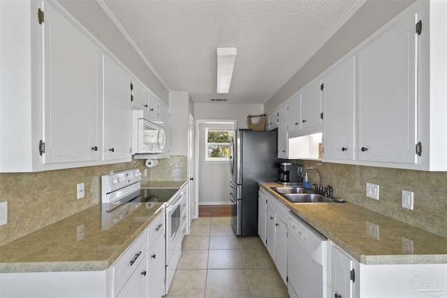 kitchen featuring light tile patterned floors, white appliances, a sink, visible vents, and white cabinets