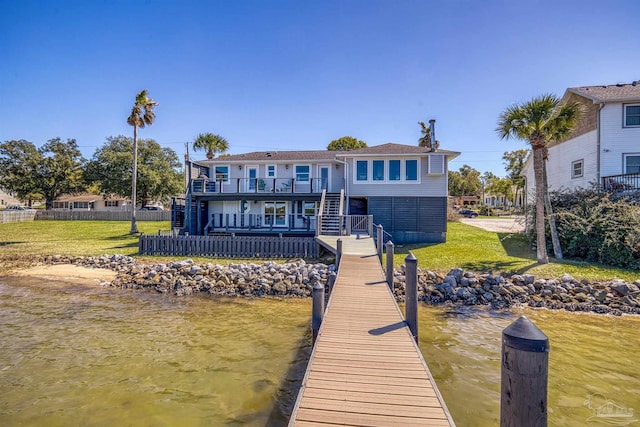 dock area with stairs, fence, a lawn, and a deck with water view