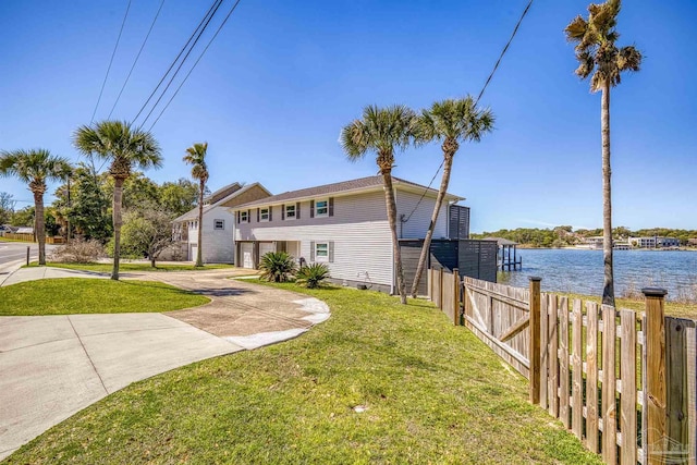 view of front of house with driveway, a front yard, fence, and a water view