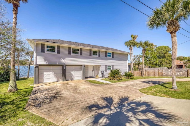 view of front of house with a front yard, driveway, an attached garage, and fence