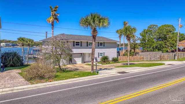 view of front of property with driveway, an attached garage, and fence