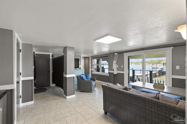 living room featuring baseboards, a textured ceiling, and light tile patterned flooring