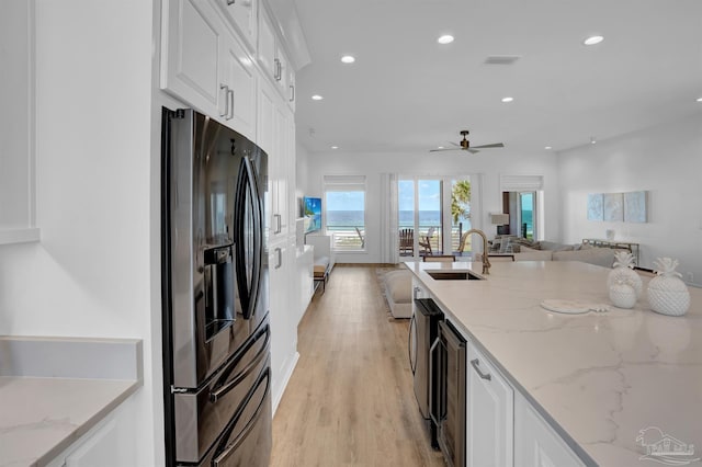 kitchen featuring light wood-type flooring, white cabinets, ceiling fan, stainless steel fridge, and sink