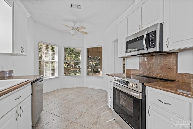 kitchen with decorative backsplash, stainless steel appliances, white cabinets, and light tile patterned flooring