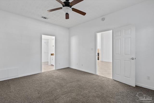 unfurnished bedroom featuring light carpet, a walk in closet, and ceiling fan