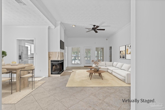 tiled living room with a premium fireplace, crown molding, ceiling fan, and a textured ceiling