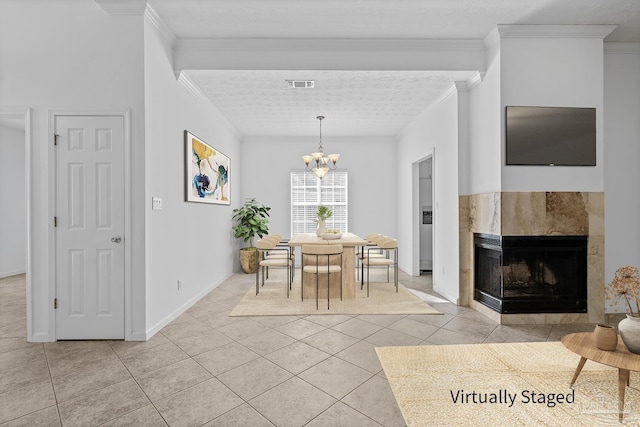 dining area with a chandelier, a textured ceiling, light tile patterned floors, ornamental molding, and a tile fireplace