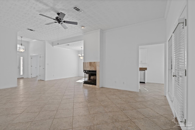 unfurnished living room with crown molding, a textured ceiling, light tile patterned flooring, a tiled fireplace, and ceiling fan with notable chandelier