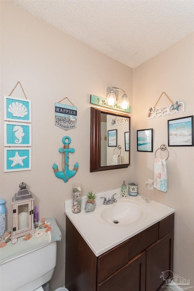 bathroom featuring toilet, a textured ceiling, and vanity