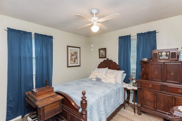 bedroom with a ceiling fan, a textured ceiling, and light wood finished floors