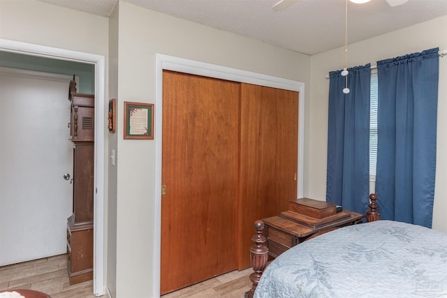 bedroom with a textured ceiling, a closet, light wood-type flooring, and a ceiling fan