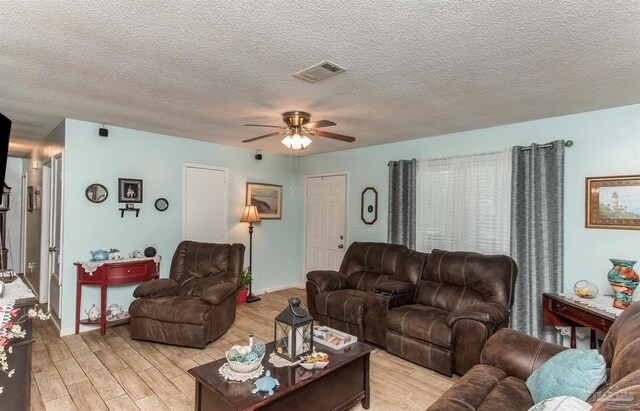 living room with light hardwood / wood-style floors, a textured ceiling, and ceiling fan