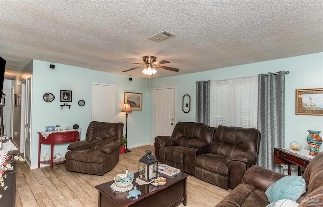 living room with baseboards, visible vents, a ceiling fan, a textured ceiling, and light wood-style floors