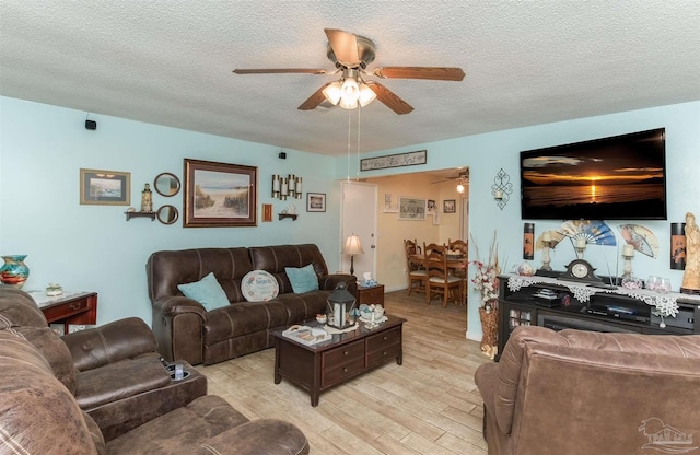 living area with light wood-type flooring, ceiling fan, and a textured ceiling