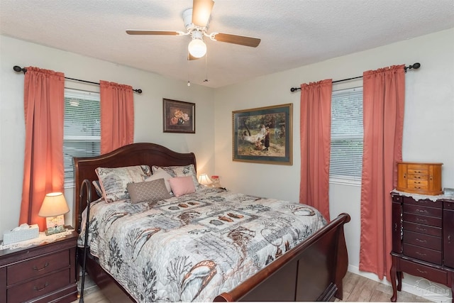 bedroom with a textured ceiling, ceiling fan, and light wood finished floors