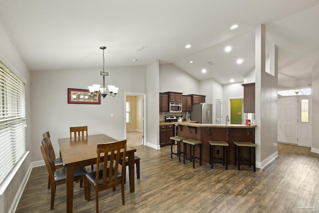 dining room featuring dark wood-type flooring, a healthy amount of sunlight, high vaulted ceiling, and a chandelier