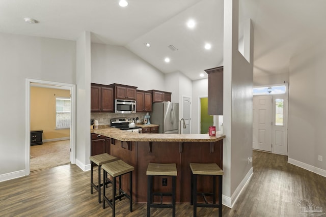 kitchen with dark wood-style flooring, a kitchen bar, stainless steel appliances, and light countertops