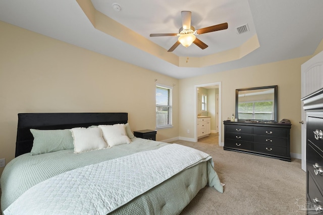 bedroom with light colored carpet, a raised ceiling, visible vents, ceiling fan, and baseboards